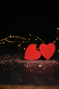 Karanlık bir arka planda, ışıkların ışığında, iki kalp yan yana.