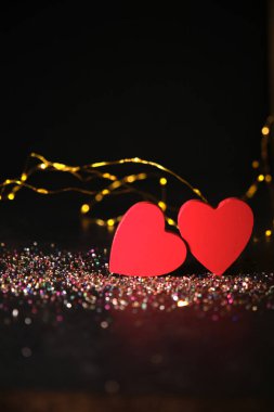 Karanlık bir arka planda, ışıkların ışığında, iki kalp yan yana.