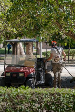 Bir park işçisi bir makine üzerinde iş yapar.