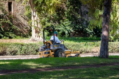 Bir park işçisi bir makine üzerinde iş yapar.
