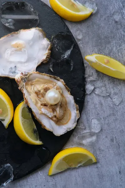 Gri bir arka planda buzun üzerinde içinde beyaz bir inci olan bir istiridye.