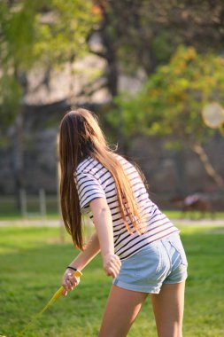 Parkta bir kız badminton oynuyor.