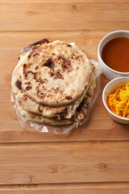 Orta Amerika geleneksel pupaları, El Salvador, Honduras ve Nikaragua 'dan gelen lezzetli bir lezzet, kırsal ahşap tepside curtido ve sosla servis edilir.