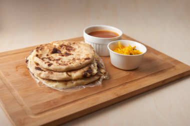 Orta Amerika geleneksel pupaları, El Salvador, Honduras ve Nikaragua 'dan gelen lezzetli bir lezzet, kırsal ahşap tepside curtido ve sosla servis edilir.