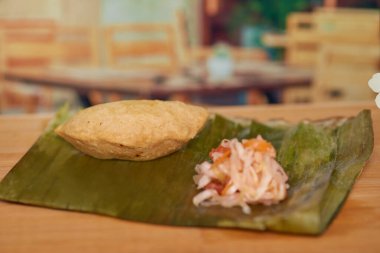 Orta Amerika 'nın El Salvador mutfağı. Pastelito Mader adlı bir et yemeği. Tahta bir masada, Curtido ile servis edilen bir restoranda..