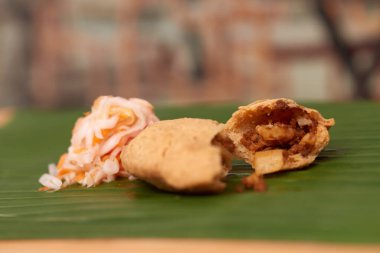 Lezzetli bir Salvador pastelito 'sunun çekici bir fotoğrafı, otantik tat ve mutfak sanatını sergiliyor, bir yaprak tarafından vurgulanmış ahşap bir yüzey üzerinde restoran tarzı bir atmosferde geçiyor.
