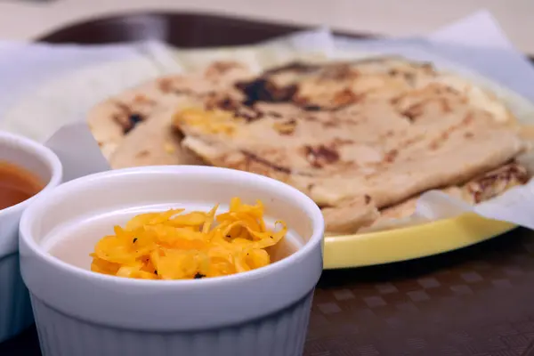 Curtido ve soslu pupusaların yakın plan fotoğrafı hazır yemek tepsisinde geleneksel bir plastik tabakta servis ediliyor..