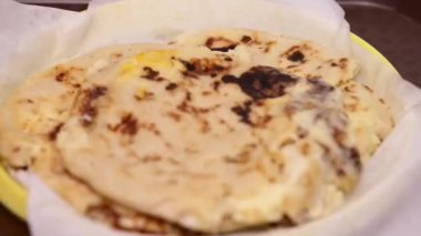 Curtido ve soslu pupusaların yakın plan fotoğrafı hazır yemek tepsisinde geleneksel bir plastik tabakta servis ediliyor..