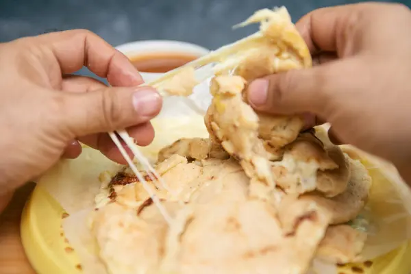 stock image Close-up of hands cutting open pupusas, revealing melted cheese strands, showcasing a delicious and traditional gourmet meal from central america, el salvador, honduras and guatemala