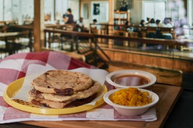Curtido ve domates soslu bir restoranda canlı bir restoranda servis edilen Salvadorlu pupusaların yakın çekimi..