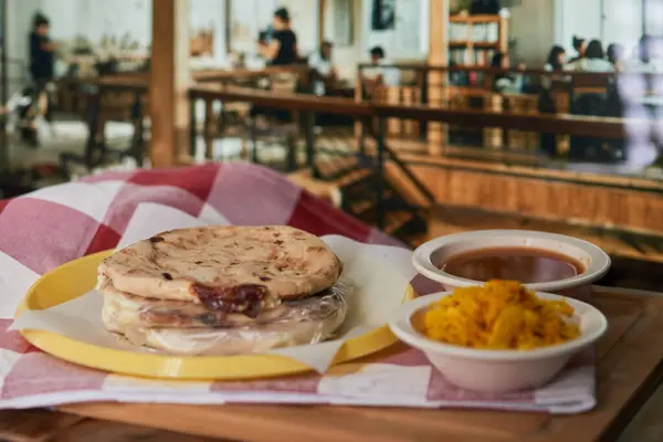 Curtido ve domates soslu bir restoranda canlı bir restoranda servis edilen Salvadorlu pupusaların yakın çekimi..