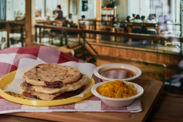 Curtido ve domates soslu bir restoranda canlı bir restoranda servis edilen Salvadorlu pupusaların yakın çekimi..
