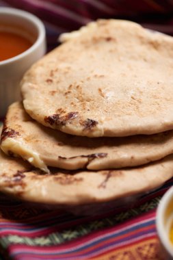 Geleneksel Orta Amerika lezzetlerini vurgulayarak ahşap bir yüzey üzerinde tamale yaprağı üzerinde servis edilen el yazısı ve soslu köpek yavruları..