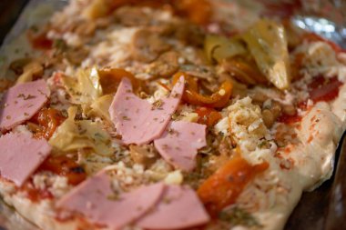 Jambon, enginar, peynir ve kırmızı biberli yeni pişmiş ev yapımı dikdörtgen pizza..