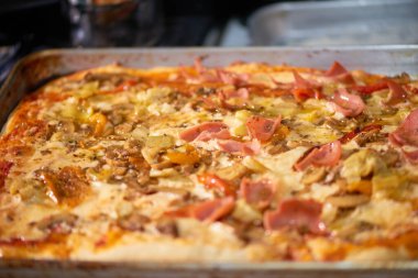 Jambon, enginar, peynir ve kırmızı biberli yeni pişmiş ev yapımı dikdörtgen pizza..