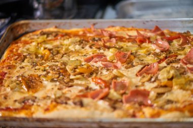 Jambon, enginar, peynir ve kırmızı biberli yeni pişmiş ev yapımı dikdörtgen pizza..