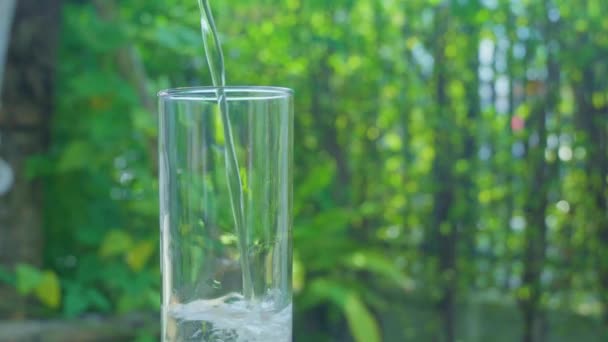 Ρίχνει Καθαρό Νερό Ένα Ποτήρι Νερό Ένα Θολό Πράσινο Φόντο — Αρχείο Βίντεο