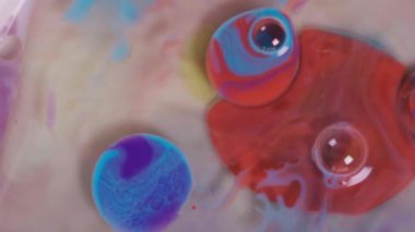 Süt, yağ ve sıvı makro zemin üzerinde hareket eden renkli akrilik boya baloncuklarının üst görünümü.