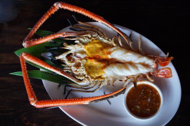 Izgara Nehir Karidesleri eti beyaz bir tabakta ve ahşap bir masada sos. Seçili odak