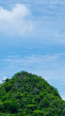Dikey video, gökyüzünde hareket eden bulutlu dağların güzel panoramik görüntüsü. Zaman ayarlı doğa videosu