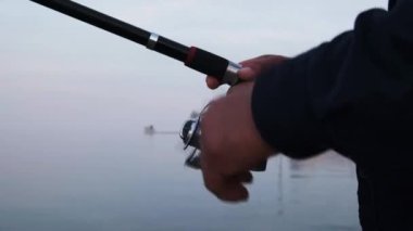 Handle rotation with reel of fishing rod against of orange sunset slow motion. 