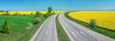 Mavi gökyüzünün altındaki yeşil ve sarı alanlar arasındaki boş otoyola panoramik manzara