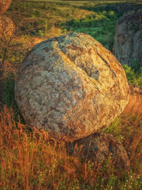 Güneşin altın ışığında büyük yuvarlak granit kaya parçasına portre görünümü
