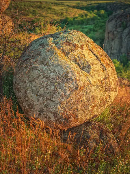Güneşin altın ışığında büyük yuvarlak granit kaya parçasına portre görünümü