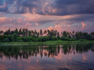 Ormanın üzerindeki bulutlarla nehir manzarası ve kopyalama alanı ile alacakaranlıkta suda yansımalar