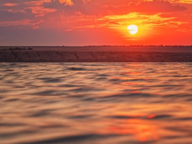 Gün batımında kırmızı bulutlarda deniz manzarası ve fotokopi uzayı ile pürüzsüz su.