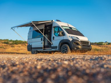Plajdaki beyaz karavana yakından bakın. Sabah şafağı açık olsun.