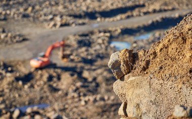 Blurred silhouette of an excavator against a clear stone background. Career concept