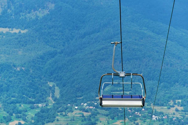 Ski lift chair hanging on a cable against the backdrop of summer mountains