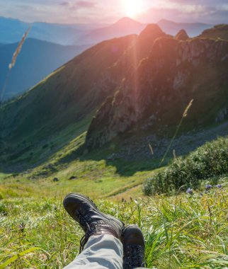 Ağır dağ botlarıyla gezen bir turistin bacakları güzel, kayalık dağların arka planına karşı. Karpat Dağları 'nda resim gibi bir sabah