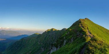Gökyüzüne karşı yeşil dağın huzurlu manzarası gerçekten nefes kesici.