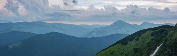 Dramatik gökyüzü ile dağ sabahı manzarası. Bulutlu gökyüzünün altındaki görkemli dağ sırasının yatay manzarası