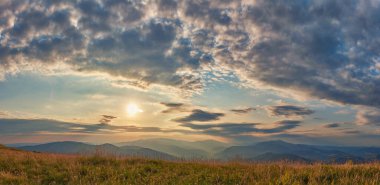 Dramatik bulutlu gökyüzü, Karpatya dağlarında gün batımı. Resimli bir yaz akşamı Dağın tepesinde