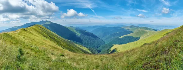 Pofuduk beyaz bulutların altında yeşil dağların büyüleyici panoramik görüntüsü doğanın dingin güzelliğini ve geniş vahşi doğayı gözler önüne seriyor..