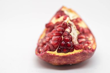 Bir parça kırmızı, olgun bir nar tanesi. Beyaz arka planda sulu, lezzetli meyveler.