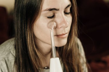 Kadın yüzü için yüksek frekanslı darsonval aygıt kullanıyor. Yüksek kalite fotoğraf