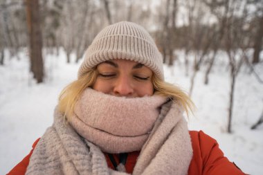 Şapkalı ve eşarplı bir kız kışın üşür ve selfie çeker. Yüksek kalite fotoğraf