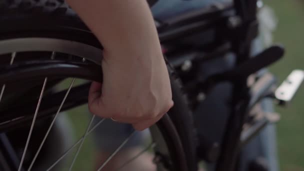 坐在轮椅上的残疾女孩移动杠杆 白天在公园里 — 图库视频影像