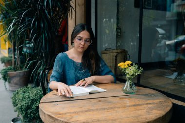 Kafedeki bir masada elinde defterle genç bir kız. Yüksek kalite fotoğraf