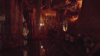 Alghero, İtalya - 1 Mayıs 2024 Neptunes Grotto 'yu ziyaret eden turistler sarkıtlarla dolu bir mağarayı geziyorlar. Yüksek kalite 4k görüntü
