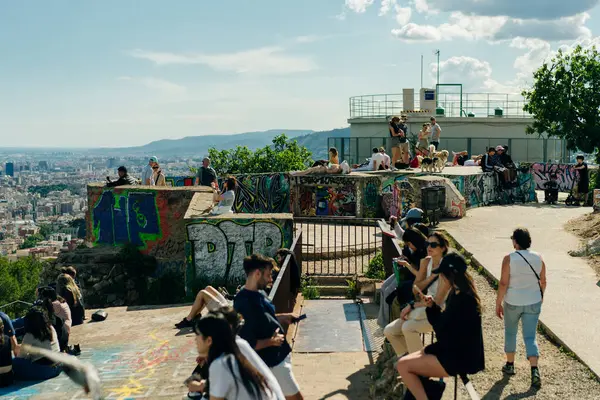 stock image people look at the view of the city from the Bunkers del Carmel on a clear sky in Barcelona, Spain - may 2 2024. High quality photo