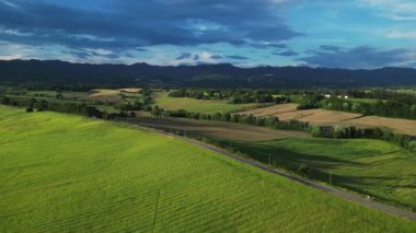 Gündoğumunda yeşil tepeleri ve tarım arazileri olan klasik Toskana manzarası. İtalya, Toskana 'daki yeşil yay tarlalarının ve tepelerin havadan görüntüsü. Yüksek kalite 4k görüntü