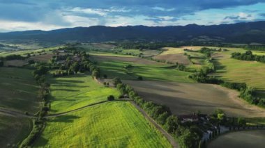 Gündoğumunda yeşil tepeleri ve tarım arazileri olan klasik Toskana manzarası. İtalya, Toskana 'daki yeşil yay tarlalarının ve tepelerin havadan görüntüsü. Yüksek kalite 4k görüntü
