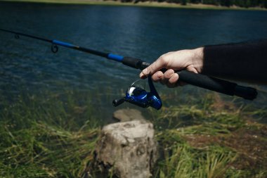 Olta kamışı tekeri yaklaşıyor, arkasında güzel bir gündoğumu olan bir adam balık tutuyor. ABD