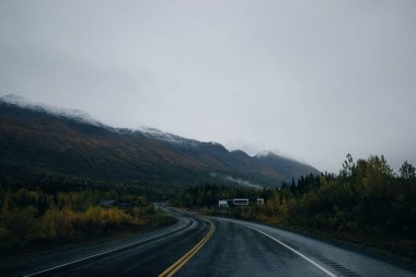 Scenic Route, Alaska Hwy, during a sunny and cloudy day. Mountains in Background. High quality photo clipart