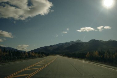 Scenic Route, Alaska Hwy, during a sunny and cloudy day. Mountains in Background. High quality photo clipart